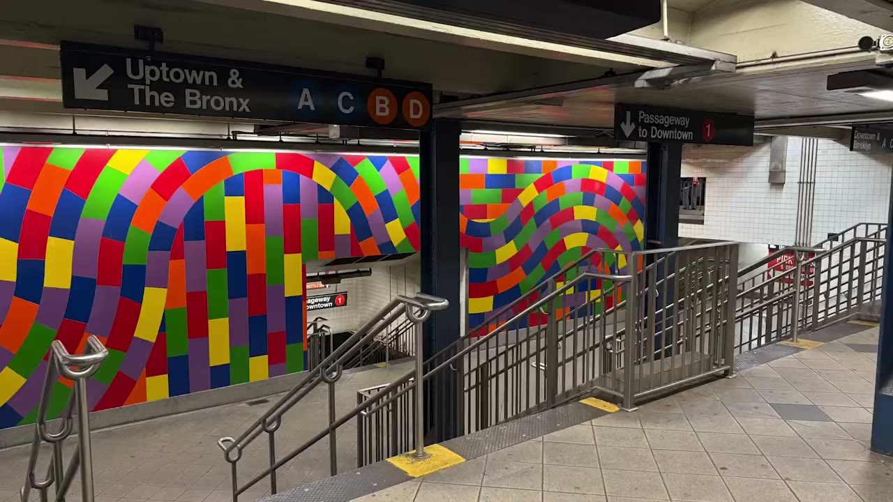 A subway station with a multicoloured mosaic wall and an empty concourse, photographed