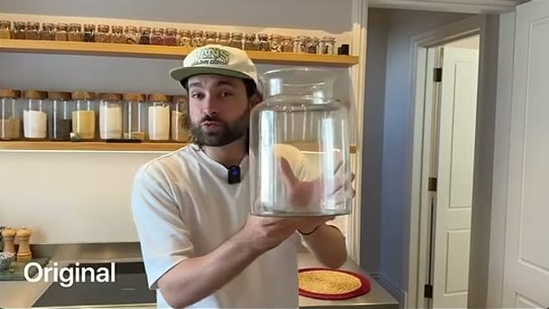 Rourke in a cap holding an empty glass jar in his kitchen