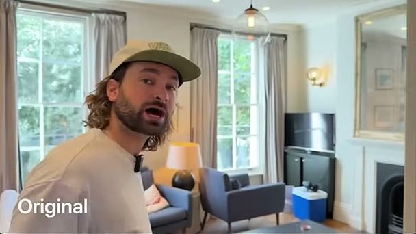 Rourke in a cap talking to camera in a living room
